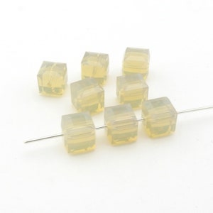 May include: A strand of eight translucent, pale yellow, square-shaped glass beads. The beads are strung on a silver wire.