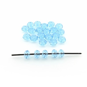 May include: A scattering of light blue faceted glass beads, with a few strung on a black wire.
