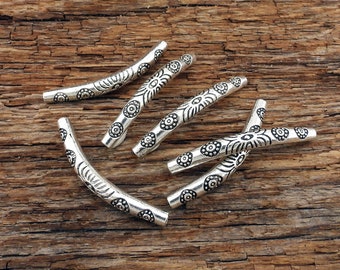 May include: Five silver metal beads with a curved shape and a decorative design of small circles and swirls.