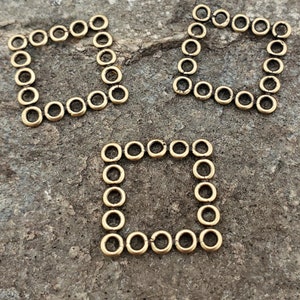 May include: Three gold-colored metal frames, each made of a series of small, connected circles, forming a square shape.