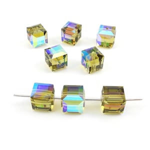 May include: A group of eight iridescent green and blue square glass beads. The beads are strung on a silver wire.
