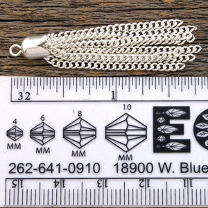 May include: A silver chain tassel with a loop at the top, measuring approximately 1 inch in length. The tassel is made of multiple strands of chain linked together.