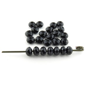 May include: A scattering of black faceted glass beads, some strung on a wire.