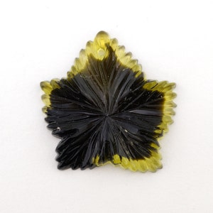May include: A green and black star-shaped pendant made of carved gemstone. The pendant has a hole at the top for a chain or cord.