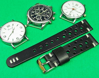May include: Black leather watch strap with white stitching and a perforated design. The strap is shown on a green surface with three silver watches.