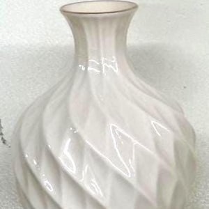 May include: A white ceramic vase with a glossy finish. The vase has a bulbous body with a textured, swirling pattern and a narrow neck. The rim is accented with a gold-colored trim. This decorative vase is suitable for floral arrangements.