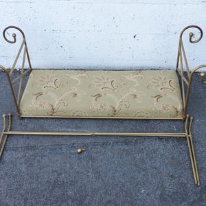 May include: A gold metal bench with a floral patterned cushion. The bench is disassembled and the cushion is separate from the frame.