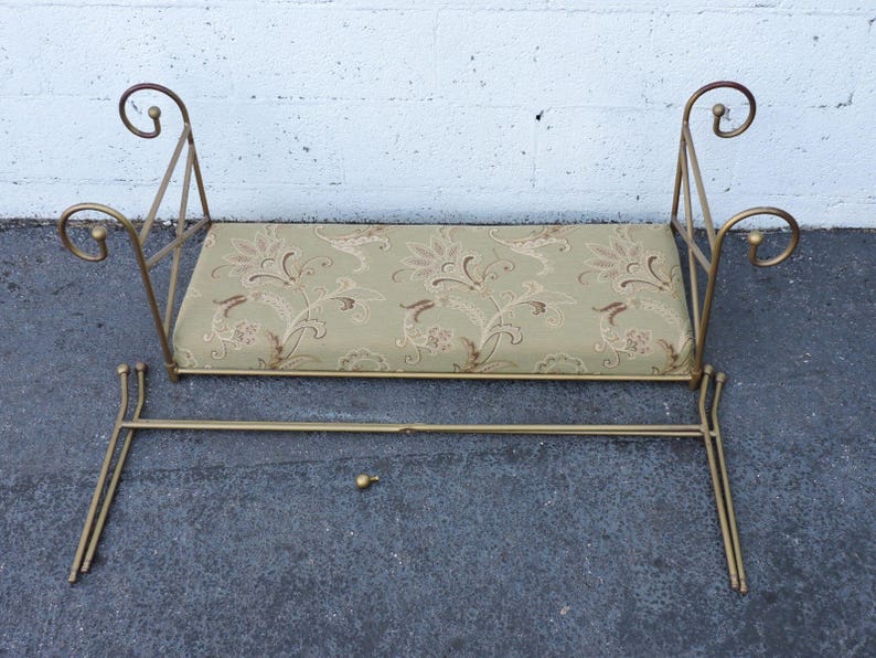 May include: A gold metal bench with a floral patterned cushion. The bench is disassembled and the cushion is separate from the frame.