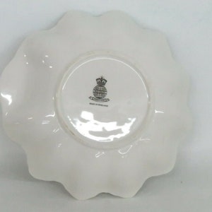 May include: White ceramic plate with a scalloped edge. The bottom of the plate has a black and white logo that says "Royal Doulton" and "Made in England."
