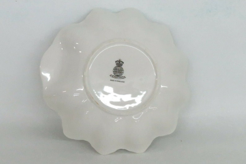 May include: White ceramic plate with a scalloped edge. The bottom of the plate has a black and white logo that says "Royal Doulton" and "Made in England."