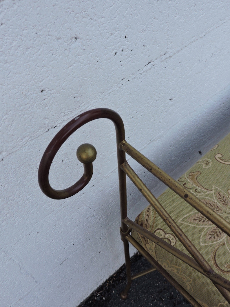 May include: A gold metal bench with a green patterned fabric cushion. The bench has a curved back with a gold ball finial.