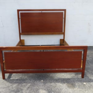 May include: A wooden bed frame with a rectangular headboard and footboard. The frame is made of dark wood and has a simple, modern design.