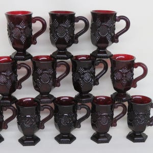 May include: Set of twelve red glass mugs with a raised diamond pattern. The mugs have a handle and a footed base.