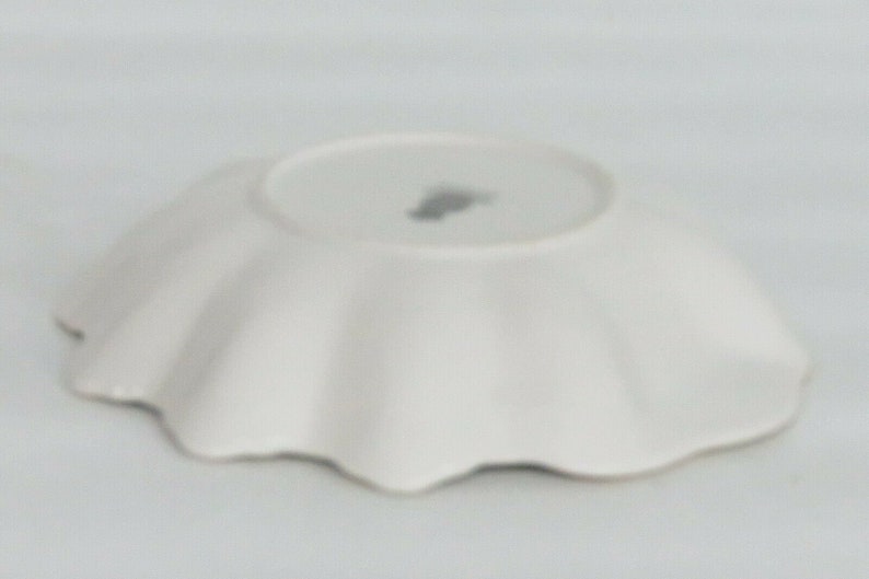 May include: White ceramic plate with a scalloped edge. The plate is empty and has a small mark on the bottom.