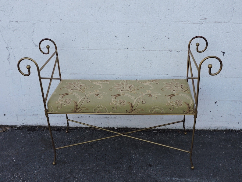 May include: A gold metal bench with a floral patterned cushion. The bench has a simple, elegant design with curved armrests.