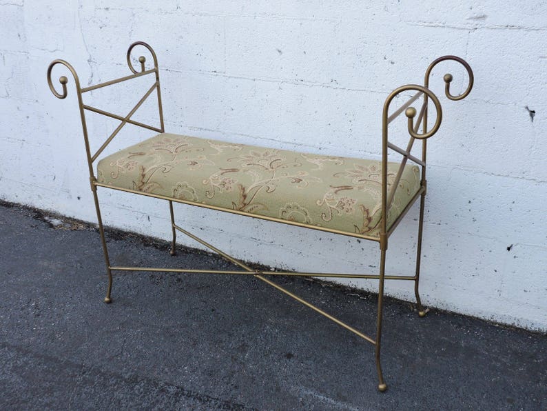 May include: A gold metal bench with a floral patterned cushion. The bench has a simple, elegant design with curved armrests.