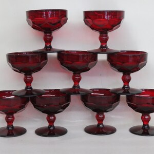 May include: Set of eight red glass stemmed goblets with a textured design. The goblets are arranged in a pyramid shape.