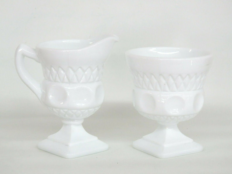 May include: A white milk glass creamer and sugar bowl set with a pedestal base and a diamond pattern.