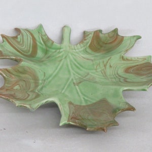 May include: A green and brown ceramic leaf-shaped serving dish with a marbled glaze.