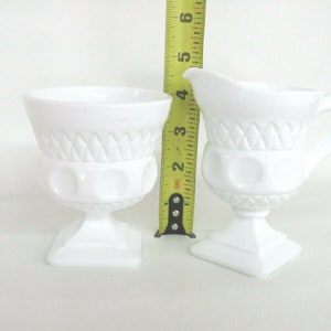 May include: White milk glass creamer and sugar bowl set with a diamond pattern and raised dots. The creamer has a handle. The sugar bowl is 3 inches tall.
