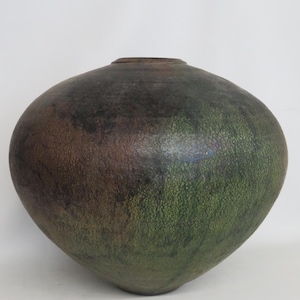 May include: A rounded ceramic vessel with a wide, bulbous body and a narrow, circular opening at the top. The surface features a mottled, textured finish with blended tones of deep forest green, dark brown, and charcoal black throughout the exterior.