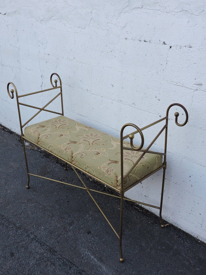 May include: A gold metal bench with a green and brown patterned cushion. The bench has a simple, elegant design with curved armrests.