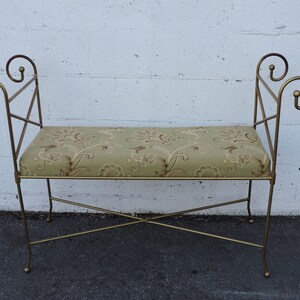 May include: A gold metal bench with a floral patterned cushion. The bench has a simple, elegant design with curved armrests.