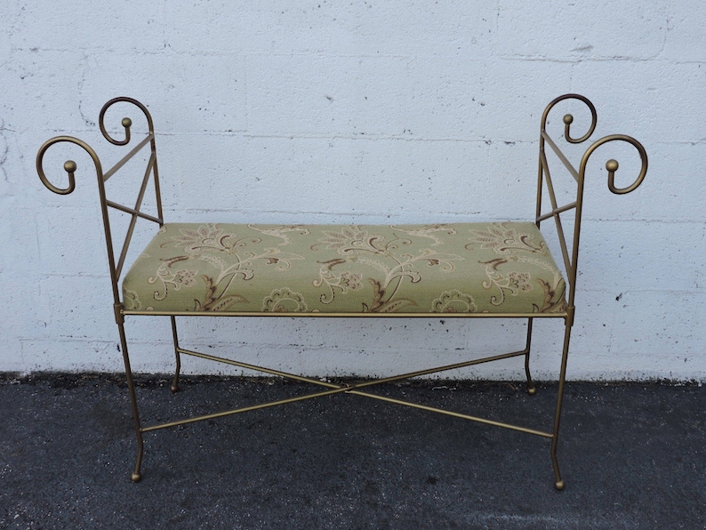 May include: A gold metal bench with a floral patterned cushion. The bench has a simple, elegant design with curved armrests.