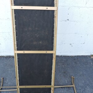 May include: A gold metal stand with a black fabric seat. The stand has a rectangular shape and is supported by four legs.