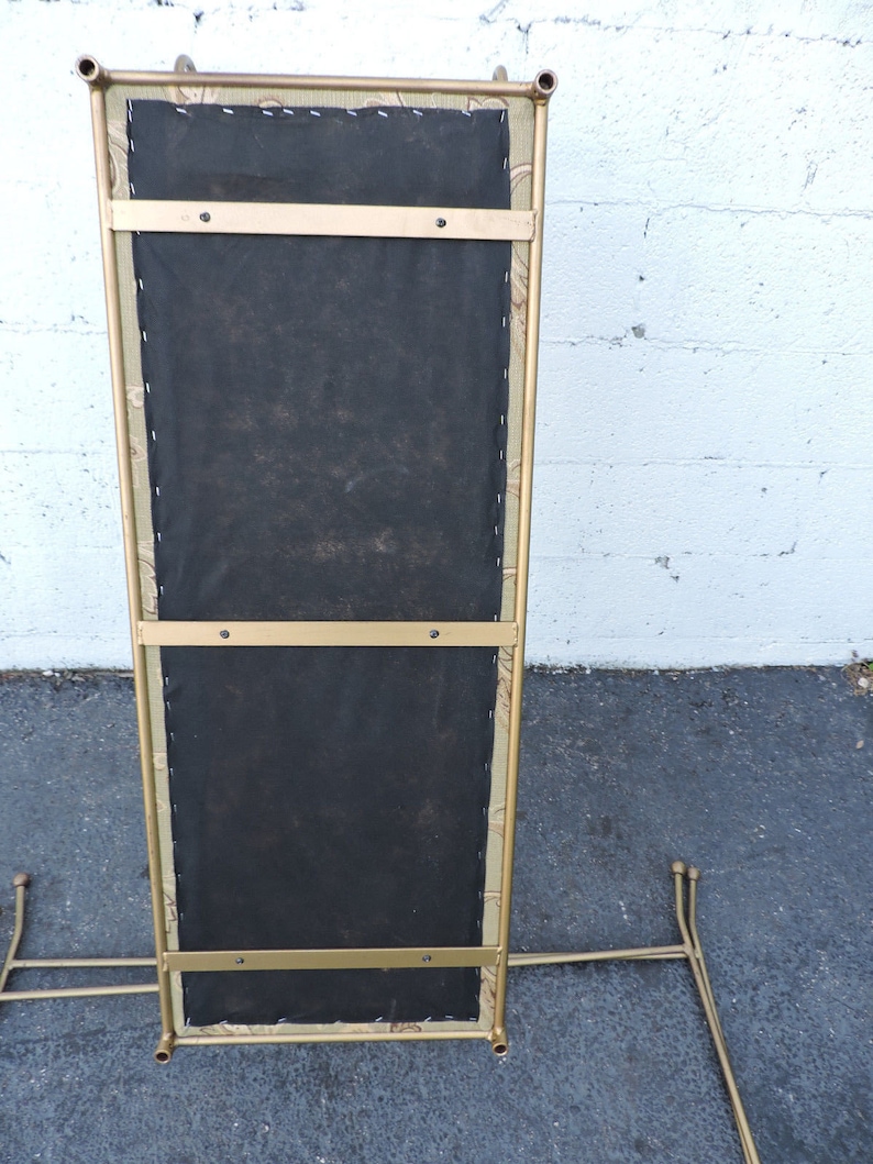 May include: A gold metal stand with a black fabric seat. The stand has a rectangular shape and is supported by four legs.