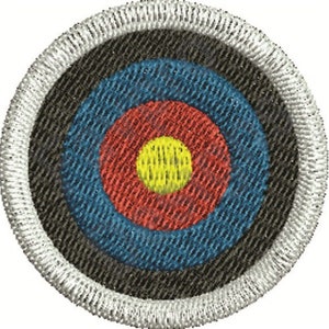 Peut inclure: Une cible ronde noire et blanche avec un centre rouge, bleu et jaune. La cible est brodée avec un tissu texturé.