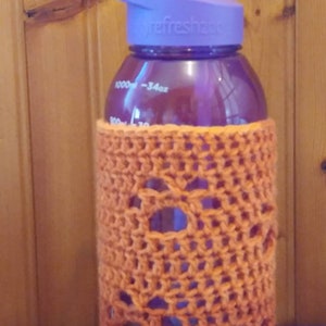 May include: A purple water bottle with a purple lid and a clear orange crocheted cover. The bottle has a label that says "refresh2go" and has markings for 1000 ml and 34 oz.