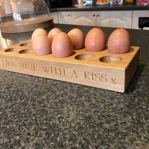 May include: A wooden egg holder with the inscription "I like mine with a kiss x" and six brown eggs inside.