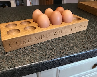 May include: A wooden egg holder with six eggs inside. The holder has the text "I like mine with a kiss" engraved on the front.