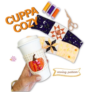 May include: A white coffee cup with a fabric cosy featuring a pumpkin applique, alongside two additional fabric cosies with star and pumpkin patterns, three spools of thread, and copper scissors. Text reads CUPPA COZY and sewing pattern.
