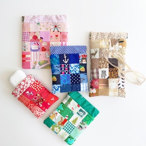 May include: Several patchwork fabric cases in different sizes and colours. The cases display a variety of patterns, including floral, nautical, and festive designs. One case holds a pair of spectacles. The cases are likely designed for storing small items.