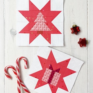May include: Two Christmas-themed fabric blocks with red star designs, one featuring a tree and the other a gift. Two red star ornaments and two candy canes are also present. The blocks are on a white background.
