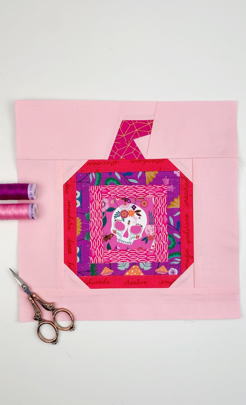 log cabin pumpkin quilt blocks in pink colors on pink background.log cabin pumpkin quilt block pattern in 5 different sizes, from 4x4 inch for ornaments to 6x6, 8x8, 10x10 and 12x12 inches for all sorts of amazing Halloween sewing projects. Use your favorite fabrics to fussy cut the center and turn these amazing beauties into your own pumpkin patch.