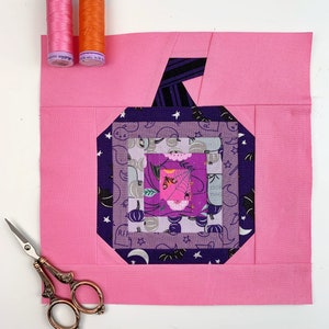 log cabin pumpkin quilt blocks in pink and purple colors on pink background.log cabin pumpkin quilt block pattern in 5 different sizes, from 4x4 inch for ornaments to 6x6, 8x8, 10x10 and 12x12 inches for all sorts of amazing Halloween sewing projects. Use your favorite fabrics to fussy cut the center and turn these amazing beauties into your own pumpkin patch.