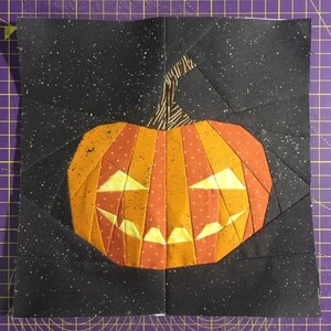 orange jack-o'-lantern quilt block on black background fabric