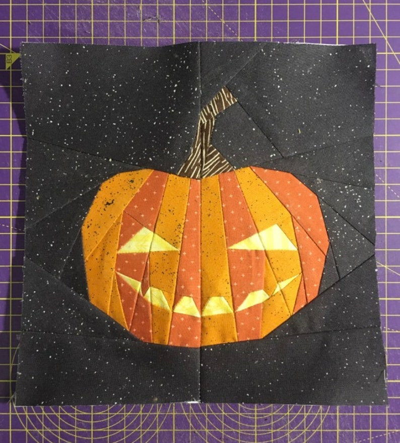 orange jack-o'-lantern quilt block on black background fabric