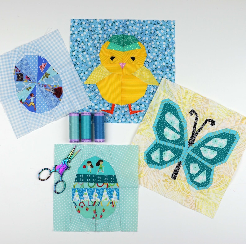 May include: Four fabric squares with different designs for a quilt. The squares feature a blue and white checkered egg, a yellow chick with a blue hat, a blue butterfly, and a blue and green egg with a pattern of girls playing.