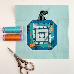 log cabin pumpkin quilt blocks in teal colors on mint background.log cabin pumpkin quilt block pattern in 5 different sizes, from 4x4 inch for ornaments to 6x6, 8x8, 10x10 and 12x12 inches for all sorts of amazing Halloween sewing projects. Use your favorite fabrics to fussy cut the center and turn these amazing beauties into your own pumpkin patch.
