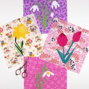 May include: Four fabric squares with different spring flower designs. Each square features a different flower, including a daffodil, a tulip, and two snowdrops. The squares are on a white background with a pair of scissors.