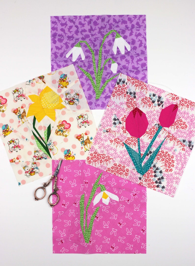 May include: Four fabric squares with different spring flower designs. Each square features a different flower, including a daffodil, a tulip, and two snowdrops. The squares are on a white background with a pair of scissors.
