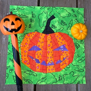 orange jack-o'-lantern quilt block on green background fabric