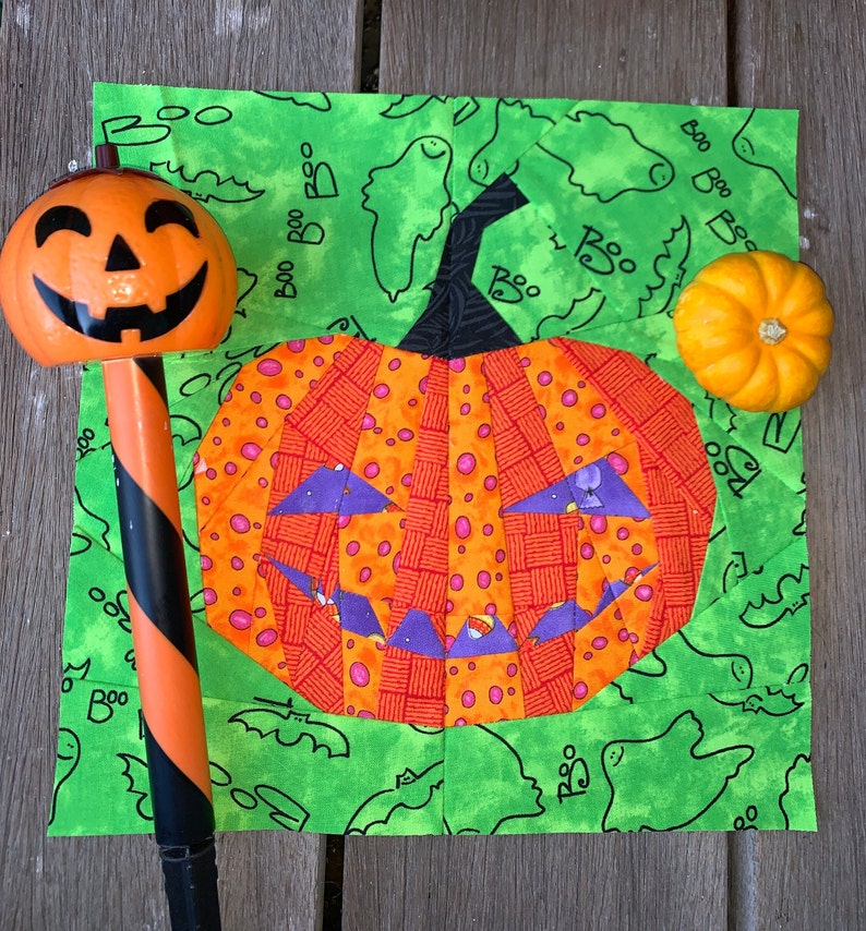 orange jack-o'-lantern quilt block on green background fabric