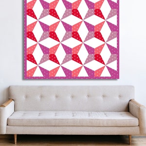 Kaleidoscope quilt pattern in red and pink colors hanging on top of a sand colored couch