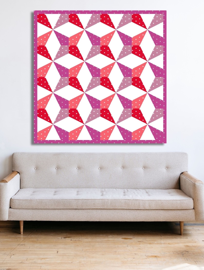 Kaleidoscope quilt pattern in red and pink colors hanging on top of a sand colored couch