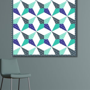 Kaleidoscope quilt pattern in green and blue colors hanging on a teal colored wall with a teal colored chair in the front